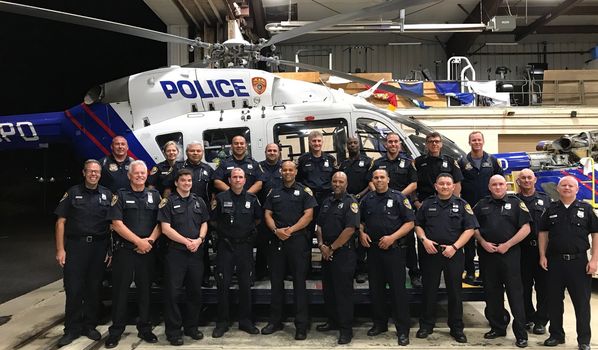 a group of police officers posing by a police helicopter